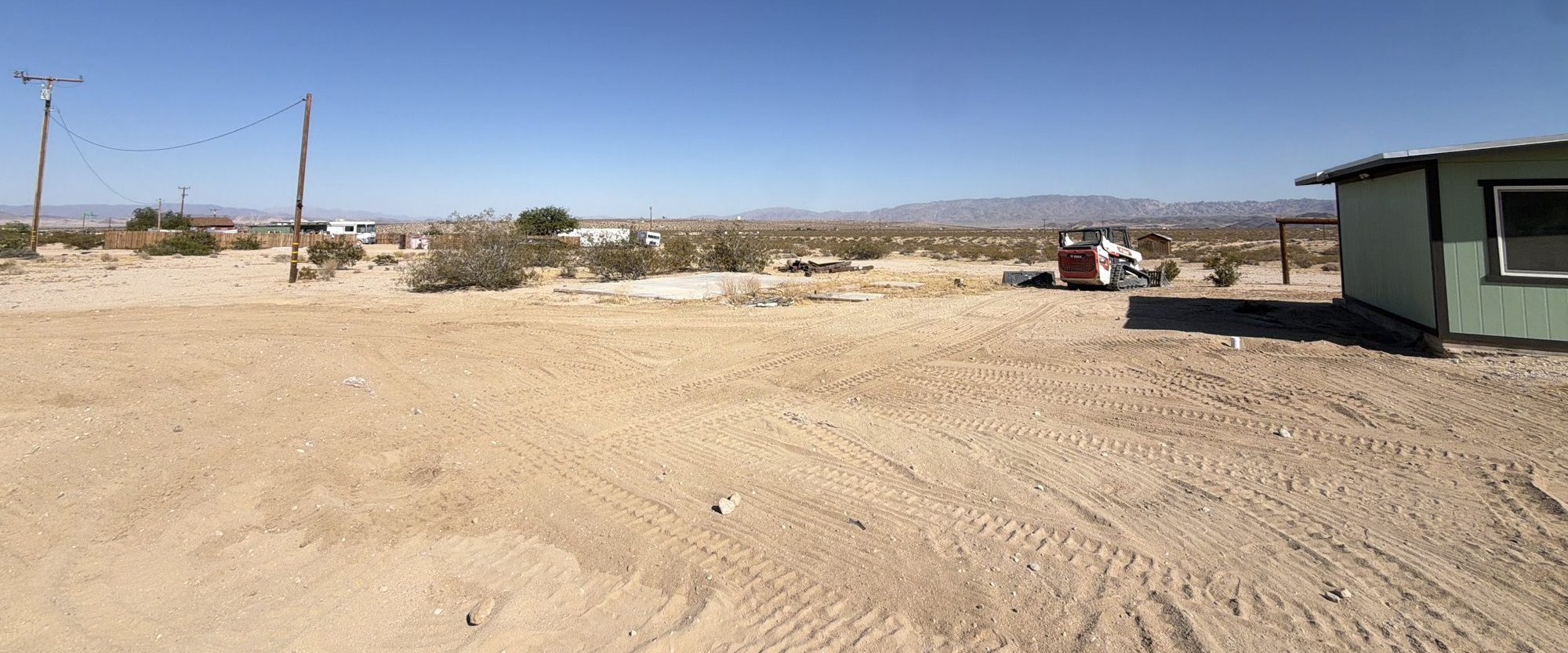 Wide graded lot with a track loader and mountain ridge