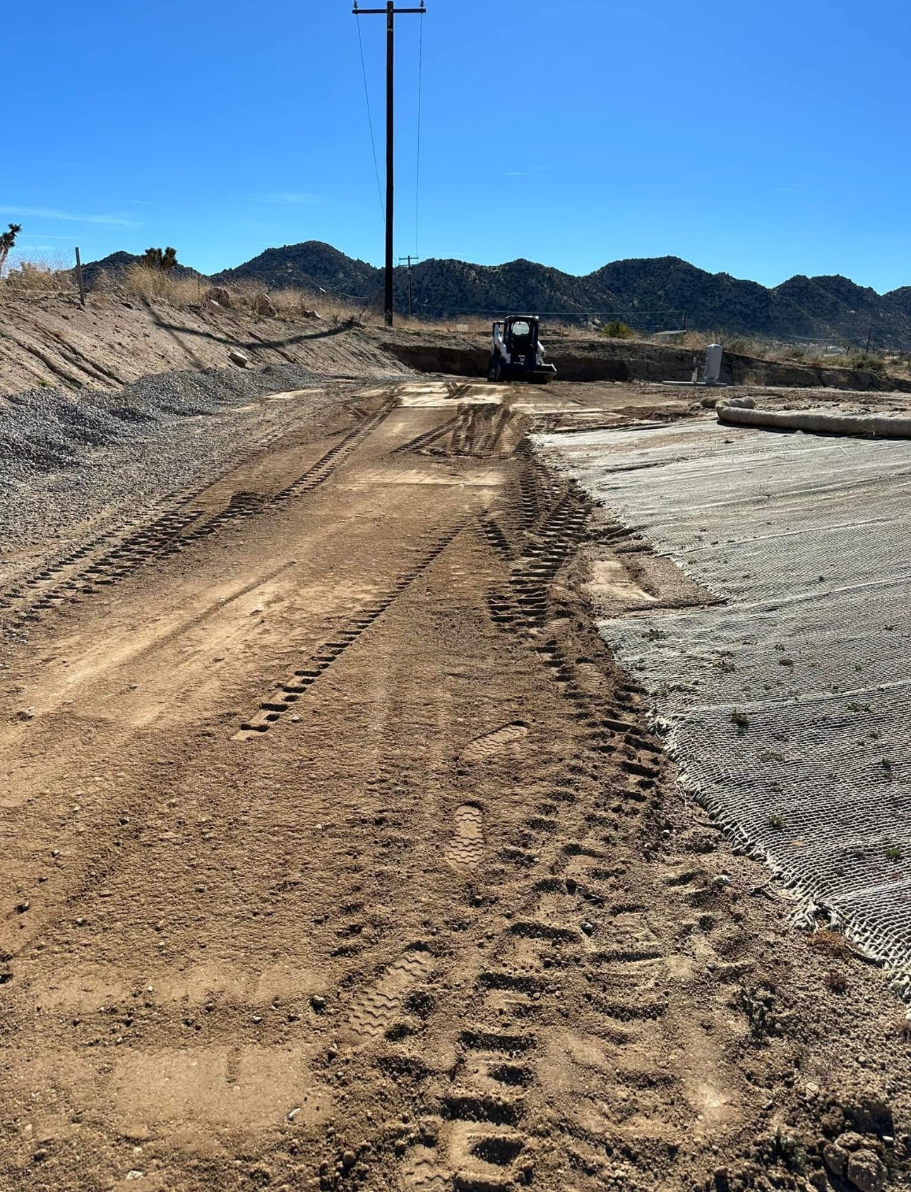 Erosion matting laid over a cut slope beside a graded road
