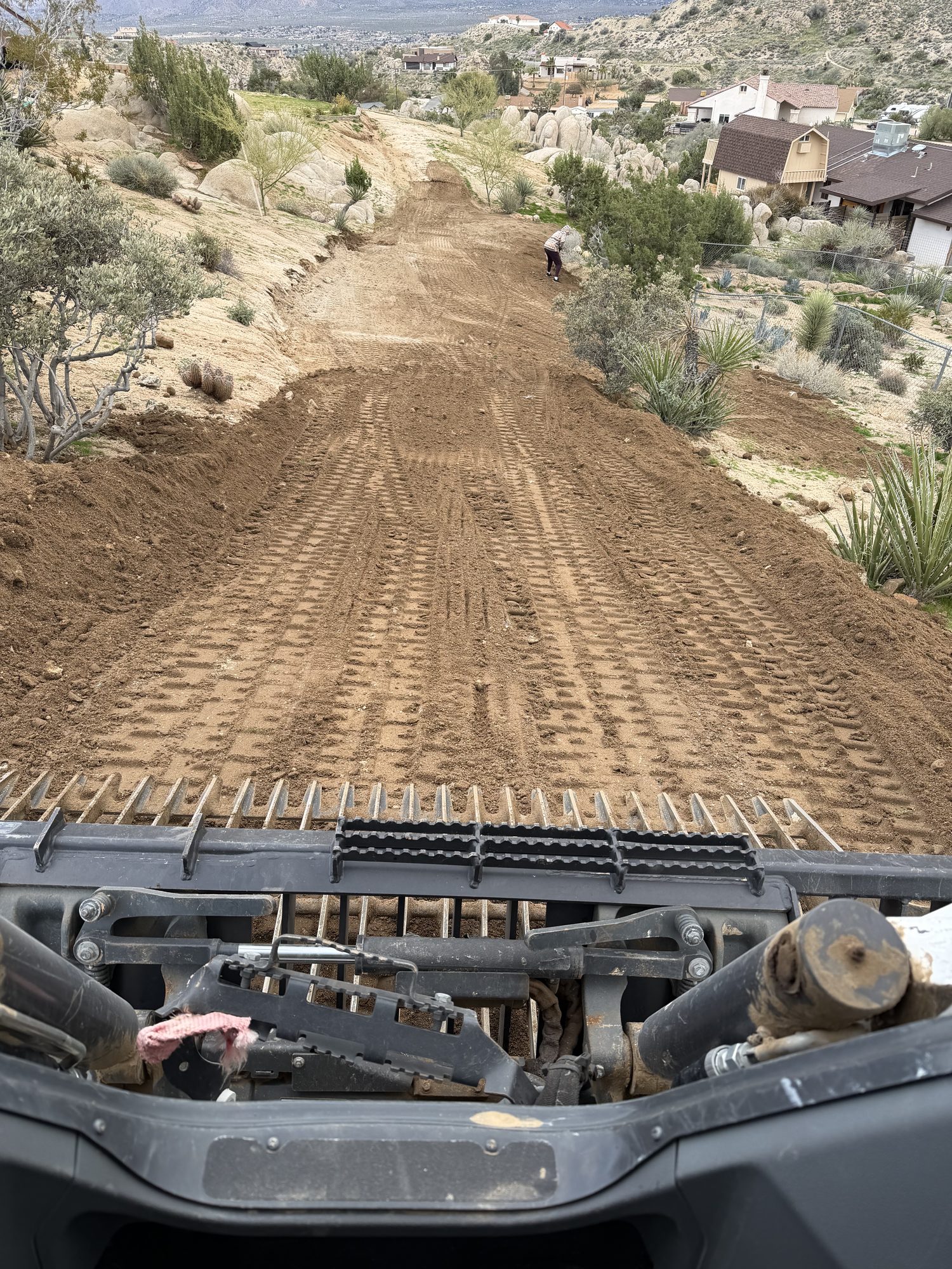 Grading a brushy hillside access route from the operator cab